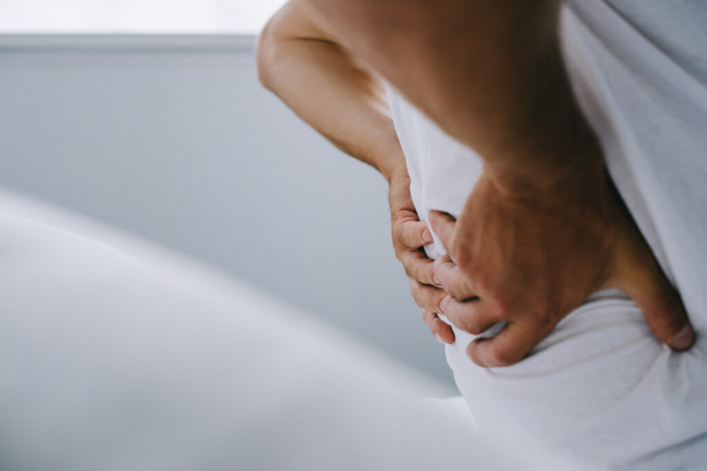 close-up partial view of man suffering from back pain on bed